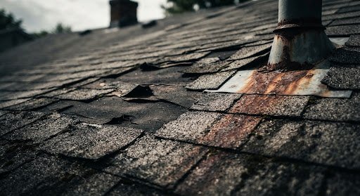Residential roof with missing shingles and moss before